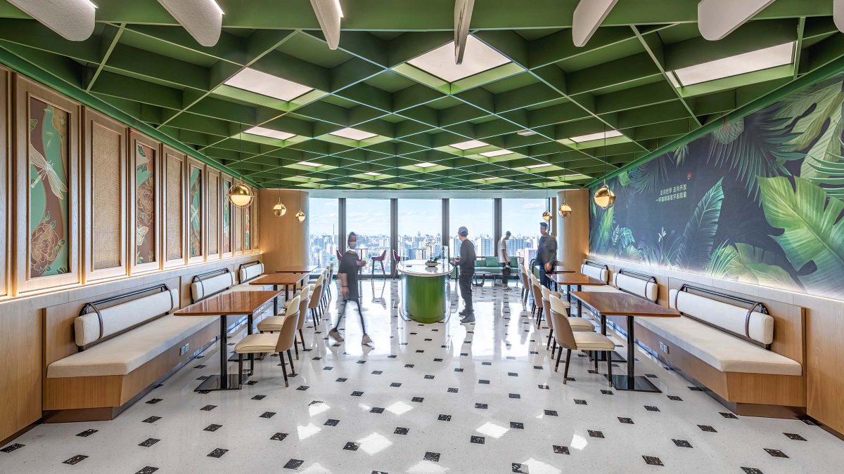 Multifunctional workspace with green slatted ceiling, plant mural wall, light birch wood paneling and seating, interior design by M Moser.